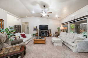 Carpeted living room featuring vaulted ceiling and a ceiling fan