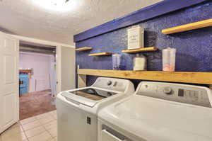 Laundry room featuring independent washer and dryer, a textured ceiling, light tile patterned floors, and water heater