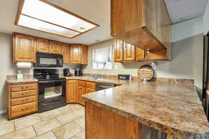 Kitchen with black appliances, kitchen peninsula, and sink