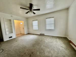 Interior space with a textured ceiling, ceiling fan, built in features, and carpet floors