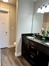 Bathroom with hardwood / wood-style floors, vanity, and toilet