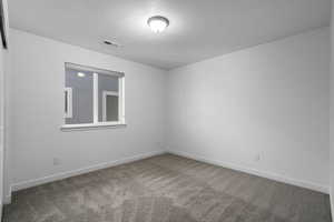 Carpeted spare room featuring a textured ceiling