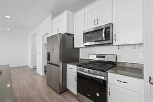 Kitchen with white cabinets, light wood-type flooring, and stainless steel appliances