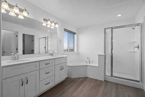 Bathroom featuring vanity, wood-type flooring, and shower with separate bathtub