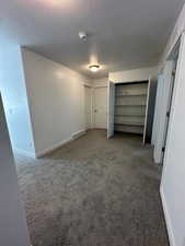 Unfurnished bedroom featuring a textured ceiling and dark colored carpet