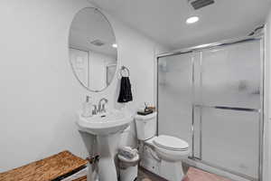 Bathroom with sink, toilet, a shower with shower door, and hardwood / wood-style flooring