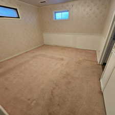 Basement with light colored carpet and a textured ceiling