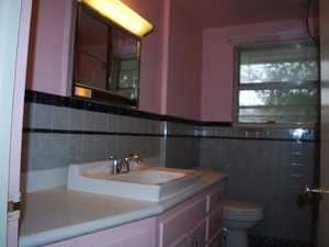 Bathroom with vanity, tile walls, and toilet