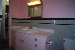 Bathroom featuring vanity, toilet, and tile walls