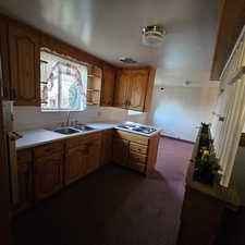 Kitchen with dark colored carpet, white gas stovetop, and sink