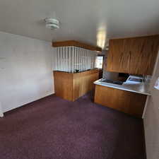 Kitchen featuring dark carpet, stainless steel stovetop, kitchen peninsula, and sink