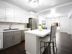 Kitchen featuring appliances with stainless steel finishes, backsplash, sink, a center island, and dark hardwood / wood-style floors