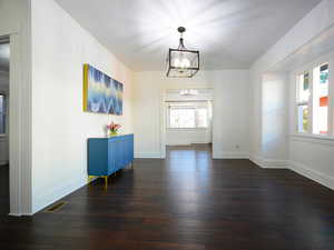 Interior space with dark wood-type flooring, plenty of natural light, and a notable chandelier