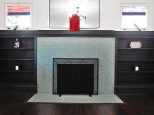 Room details with built in shelves, a fireplace, and hardwood / wood-style flooring