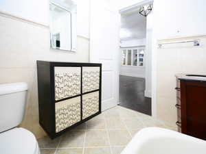 Bathroom featuring toilet, vanity, tile walls, and hardwood / wood-style flooring