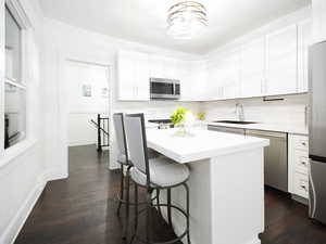 Kitchen featuring dark hardwood / wood-style flooring, sink, white cabinets, and stainless steel appliances