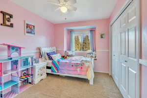 Carpeted bedroom with ceiling fan and a closet