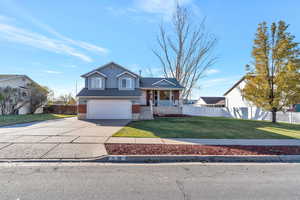 View of front of home featuring a front lawn, a porch, and a garage