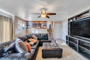 Living room with carpet flooring, ceiling fan, and a textured ceiling