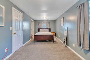 Bedroom featuring light colored carpet and a textured ceiling