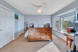 Bedroom with light carpet, ceiling fan, and two closets