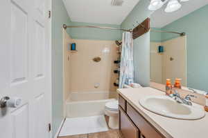 Full bathroom with tile patterned flooring, shower / bath combo with shower curtain, vanity, and toilet