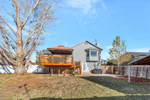 Back of property with a gazebo, a wooden deck, and a lawn