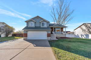 Tri-level home with a porch, a garage, and a front lawn