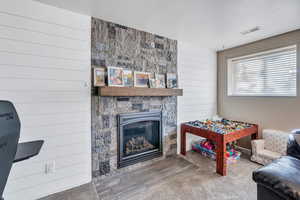 Playroom featuring wood walls, a fireplace, a textured ceiling, and hardwood / wood-style flooring