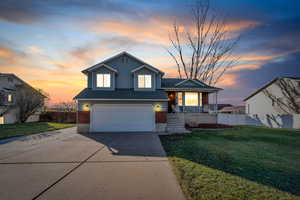 View of front of property with a porch, a garage, and a lawn