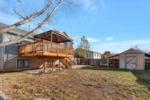 Rear view of house with a yard, a patio, a shed, and a wooden deck