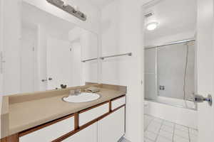 Full bathroom with tile patterned flooring, vanity, toilet, and enclosed tub / shower combo