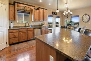 Kitchen featuring sink, hanging light fixtures, an inviting chandelier, dark hardwood / wood-style flooring, and stainless steel dishwasher