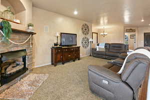 Carpeted living room featuring a fireplace and a notable chandelier