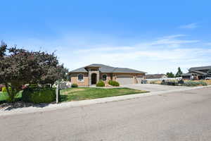 Single story home featuring a garage and a front lawn