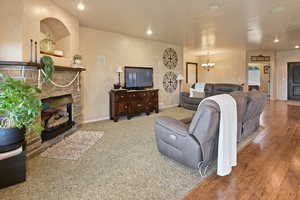 Living room with a brick fireplace, a notable chandelier, and hardwood / wood-style flooring