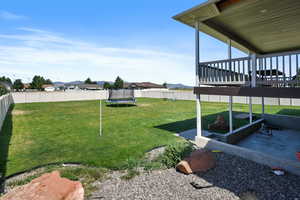 View of yard with a patio area, a deck, and a trampoline