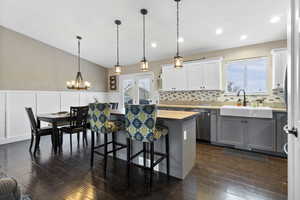 Kitchen featuring dishwasher, sink, wooden counters, decorative light fixtures, and white cabinets