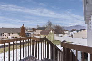 Snow covered deck with a mountain view and a shed