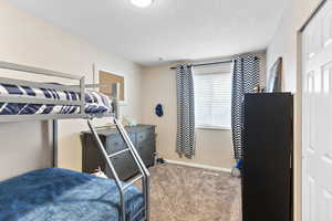 Carpeted bedroom with a textured ceiling and a closet