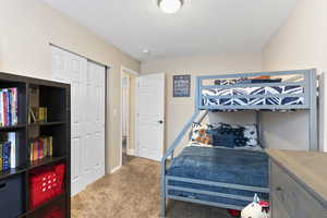 Bedroom featuring a textured ceiling, carpet floors, and a closet