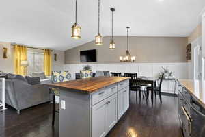 Kitchen featuring a center island, lofted ceiling, wooden counters, hanging light fixtures, and dark hardwood / wood-style floors