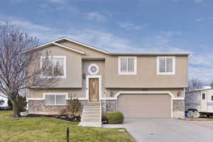 Raised ranch featuring a front yard and a garage