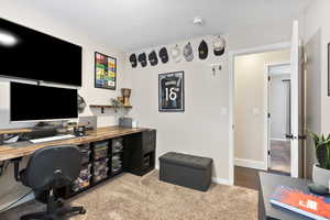 Carpeted office featuring a textured ceiling