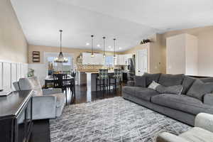 Living room with dark hardwood / wood-style flooring, lofted ceiling, and a chandelier