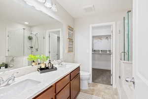 Bathroom featuring tile patterned floors, toilet, vanity, and walk in shower