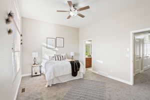 Carpeted bedroom with ceiling fan and connected bathroom