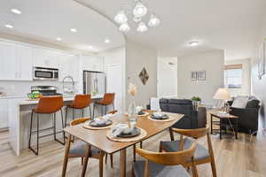 Dining area with sink, an inviting chandelier, and light wood-type flooring