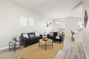 Living room with light hardwood / wood-style floors and an inviting chandelier