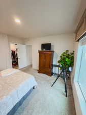 Bedroom with light colored carpet, a walk in closet, and a closet